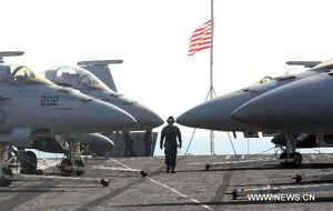 A soldier walks past the fighter jets on the deck of the U.