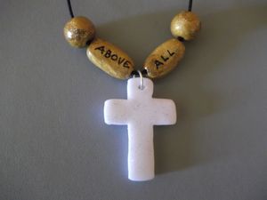 CROIXGA.52B1/Collier Croix ABOVE ALL Perle blanche/dorée Fil élastique noir 8€